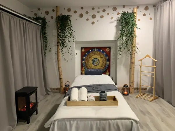 Cozy massage room with treatment bed, candles, plants, and decorative wall art