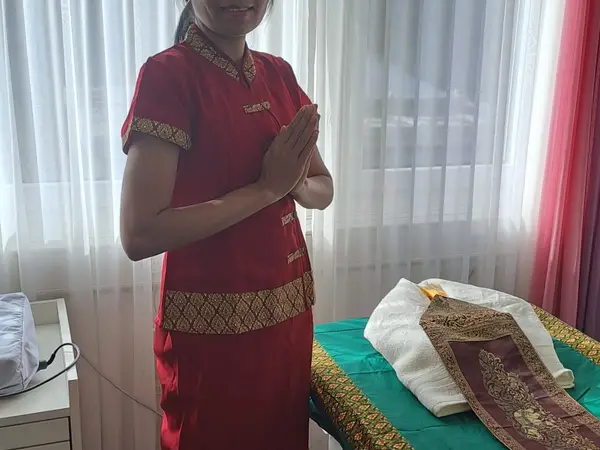 Thai massage room with practitioner in red attire beside a treatment table
