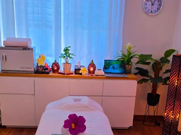 Cozy massage room with treatment bed, plants, and warm decorative lighting