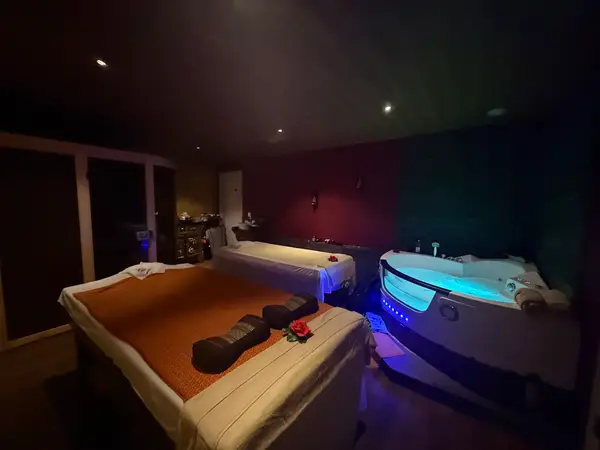 Dim massage room with two beds and a glowing spa tub