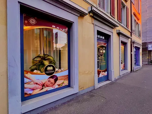 Exterior storefront windows of a Thai massage salon on a city street