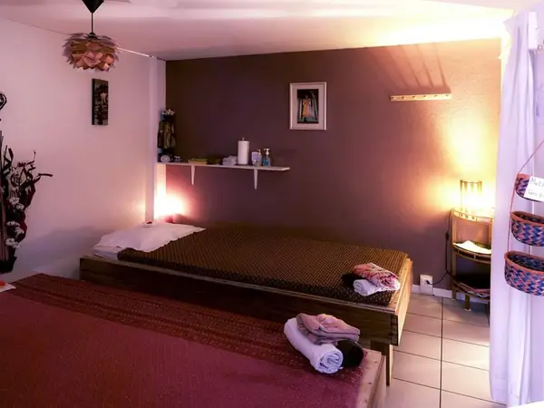 Cozy massage room with two treatment beds, soft lighting, and purple walls