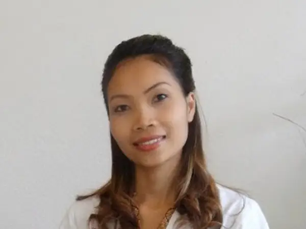 Portrait of a smiling woman against a plain white wall