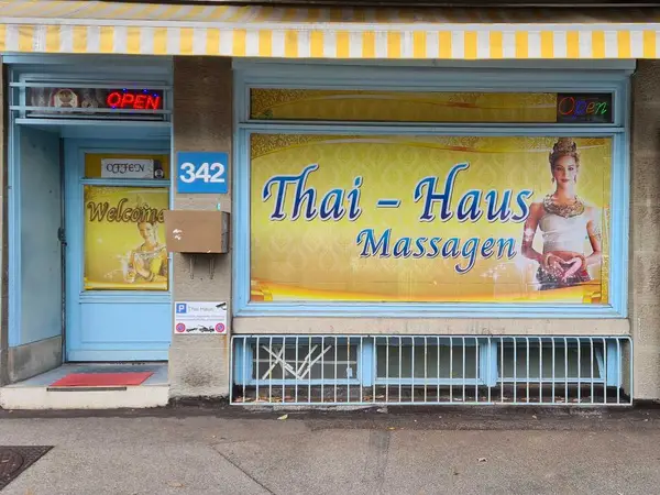 Exterior of a Thai massage salon with blue trim and bright signage
