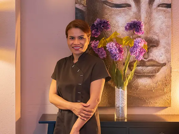 Spa reception with smiling staff, floral vase, and Buddha wall art