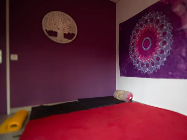 Purple massage room with red mat and decorative wall art