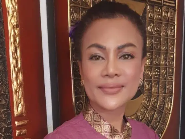 Portrait of a woman in a pink traditional top against ornate gold decor