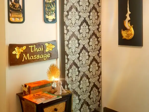 Thai massage room with ornate wall decor, sign, and warm lighting