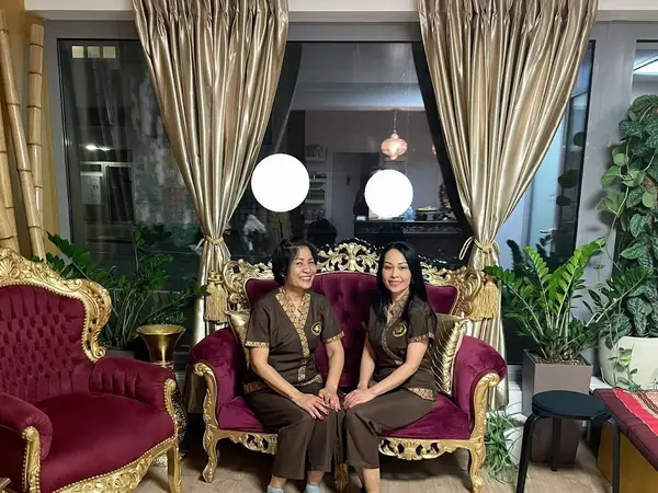 Elegant salon seating area with ornate gold and burgundy chairs, plants, and curtains