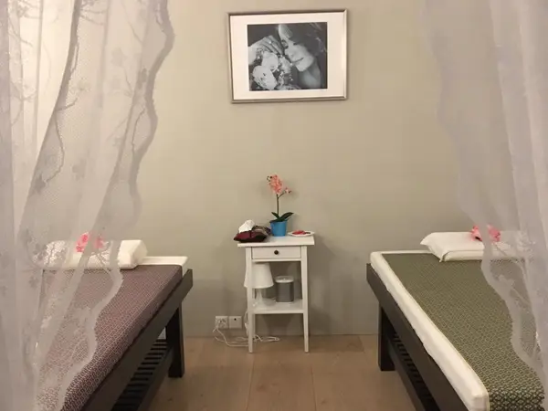 Serene massage room with two beds, lace curtains, and a small table