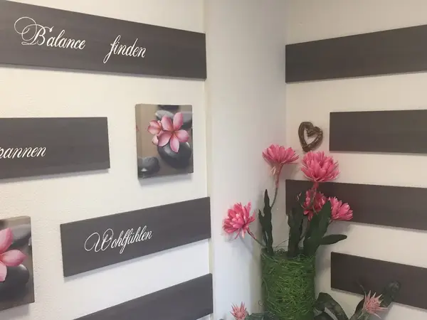 Decorative massage salon corner with floral art, dark wall panels, and pink flowers