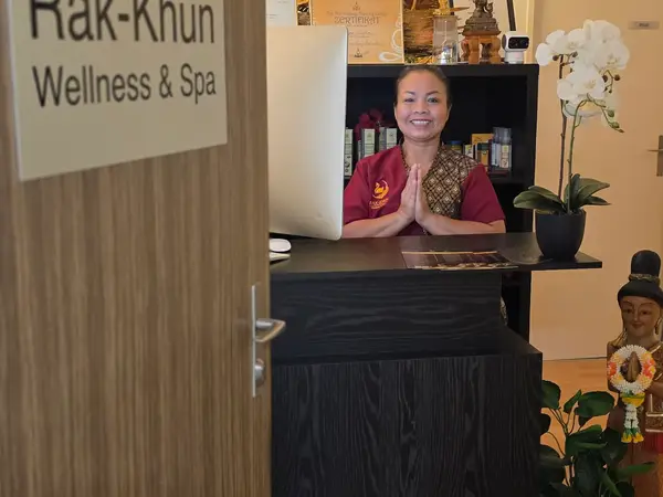 Thai massage reception with smiling staff, orchids, and a welcoming spa counter