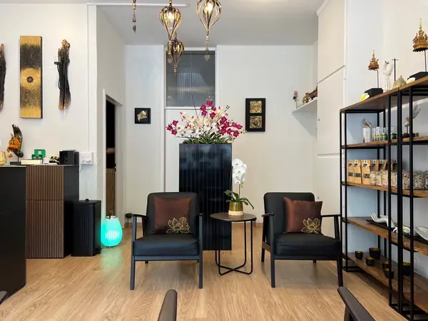 Elegant spa waiting room with black chairs, flowers, and Thai decor