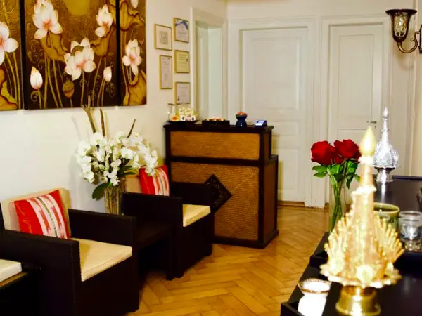 Warm spa reception with armchairs, flowers, artwork, and wooden parquet flooring