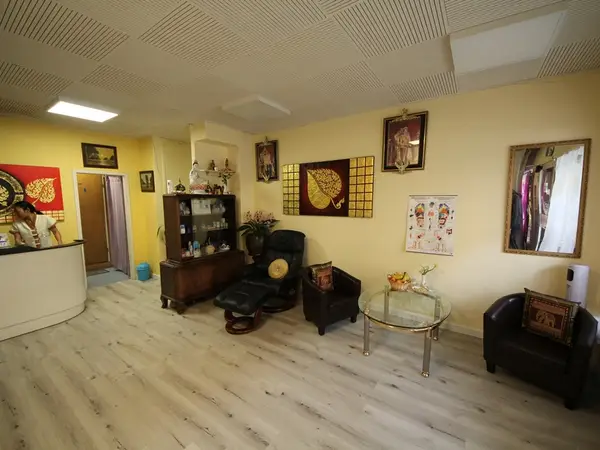 Thai massage reception room with chairs, cabinet, mirror, and framed wall art