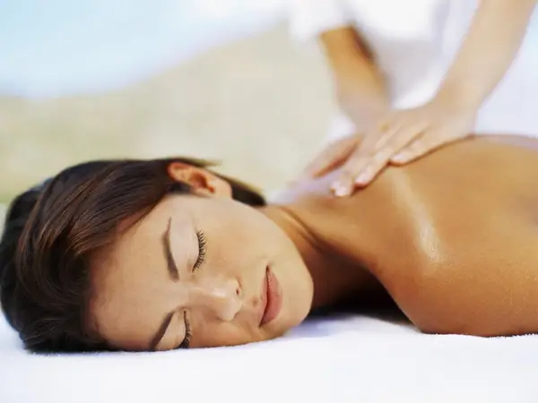 Close-up of a woman receiving a shoulder massage on a treatment table