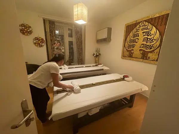 Thai massage room with two treatment beds and a therapist preparing them