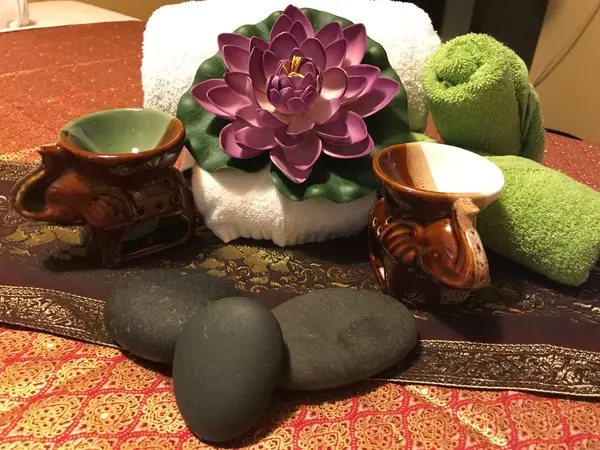 Decorative massage table arrangement with towels, lotus flower, cups, and stones