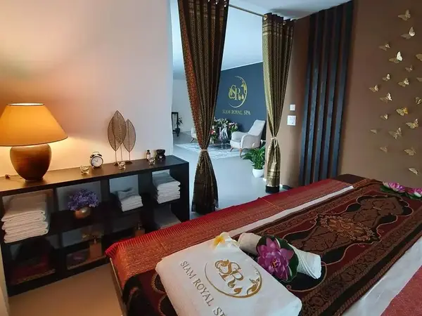 Massage room with bed, warm lamp, folded towels, and curtained spa entrance