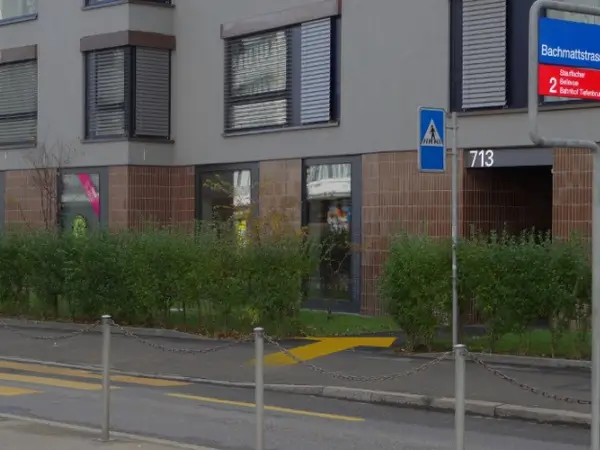 Exterior of a modern apartment building with salon windows and street signs