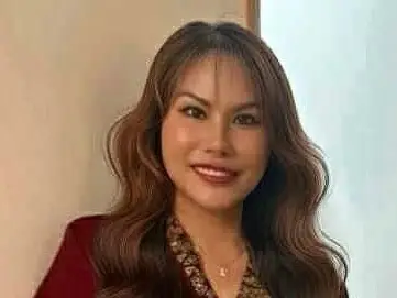 Portrait of a smiling woman against a plain indoor background