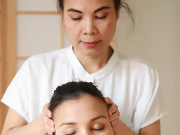 Close-up of a masseuse giving a head massage in a calm treatment room