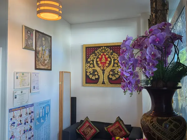 Cozy Thai massage waiting area with ornate wall art and purple flowers