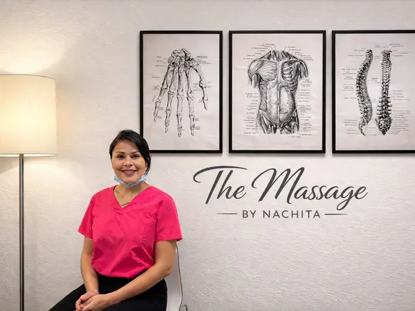 Massage salon interior with anatomical posters, floor lamp, and smiling staff member