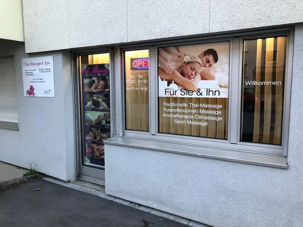 Exterior storefront of Thai Massage Lisa with window posters and open sign