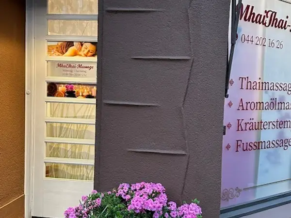 Salon exterior with window signage, doorway, and pink flowers in front