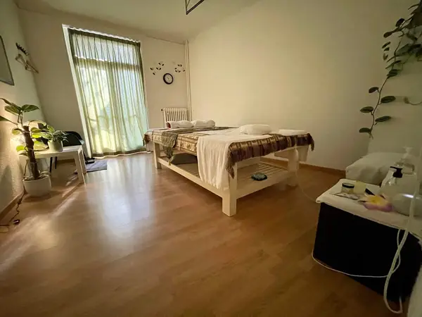 Minimal Thai massage room with treatment bed, plants, and soft natural light