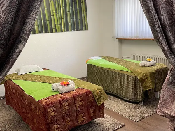 Calm massage room with two treatment beds, bamboo wall art, and curtains
