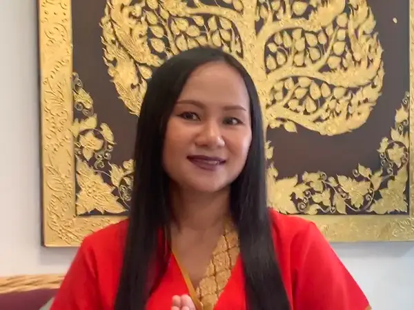 Woman in red robe before ornate gold wall art indoors