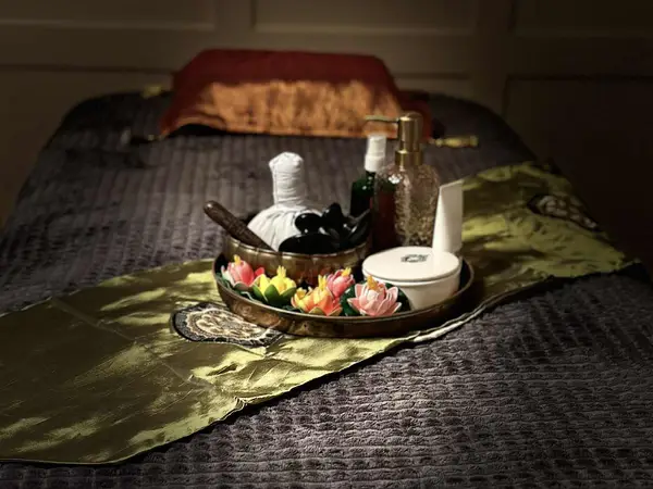 Massage table with towel, decorative tray, and spa products in dim light