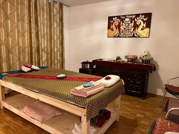 Warm Thai massage room with wooden table, curtains, and decorative wall art