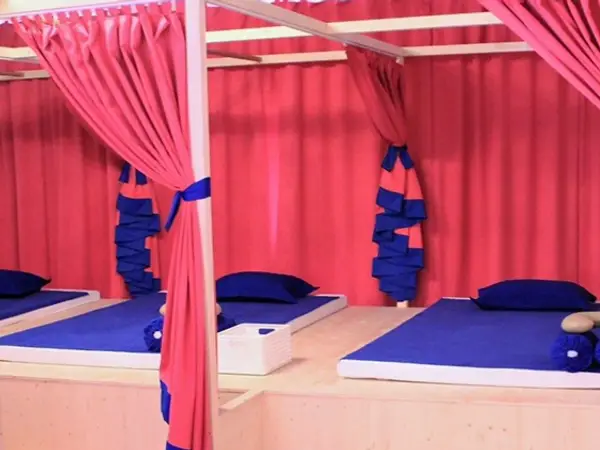 Pink-curtained massage room with blue mats and pillows on raised platforms