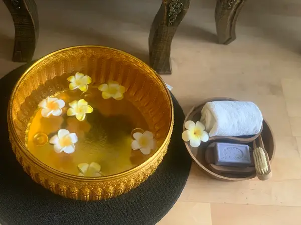 Decorative footbath bowl with floating flowers and spa towels on a tray