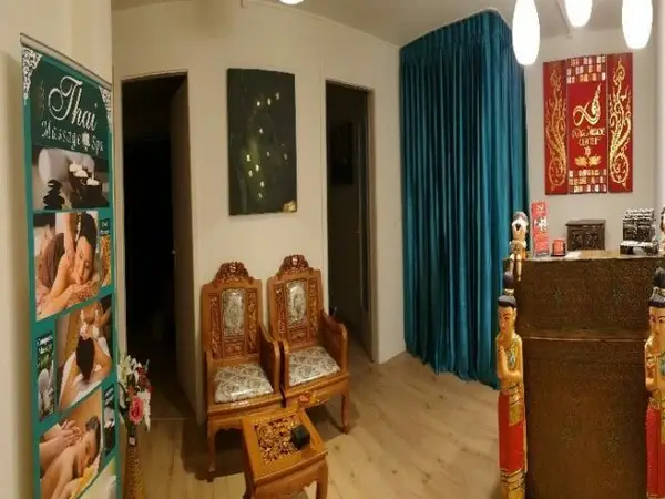 Thai massage salon reception with ornate chairs, blue curtains, and decorative statues