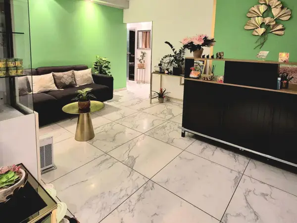 Bright reception area with green walls, black sofa, and marble-pattern tile floor