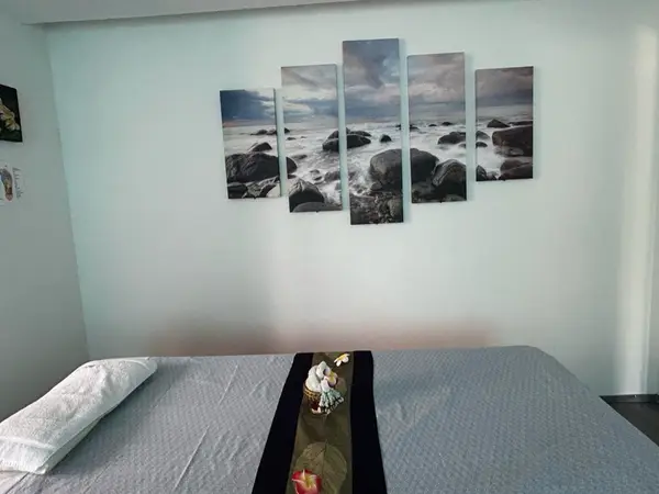 Minimal massage room with bed, folded towel, and ocean wall art