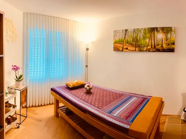 Serene massage room with treatment table, sheer curtains, and wall art
