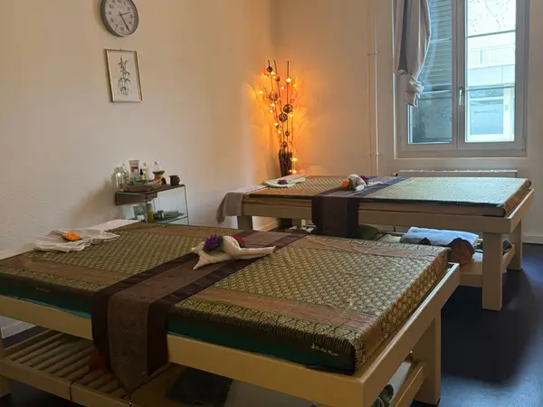Thai massage room with two treatment tables, warm decor, and window light