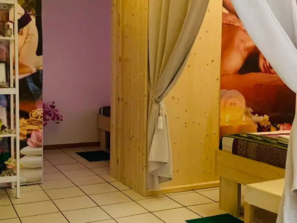 Warmly lit Thai massage room with curtains, tiles, and decorative flowers