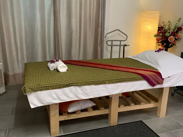 Serene massage room with treatment table, folded towels, curtain, lamp, and flowers