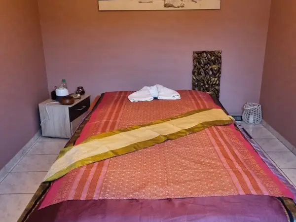 Small Thai-massage room with a covered treatment bed and side table