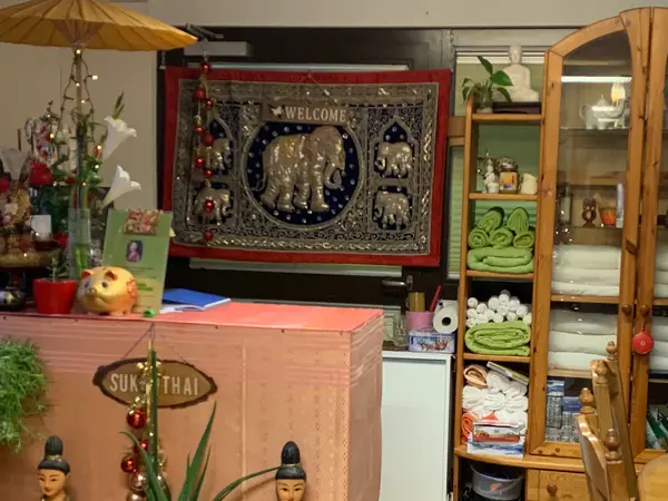 Decorated Thai massage reception with towels, elephant tapestry, and wooden cabinet