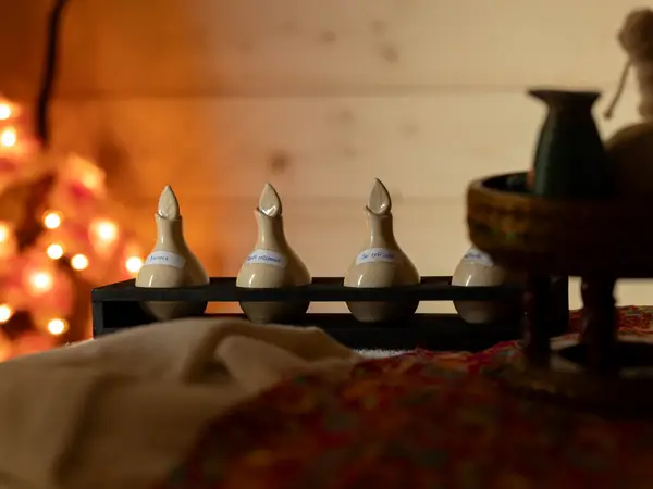 Cozy massage room with candlelight, wooden decor, and treatment bed accessories