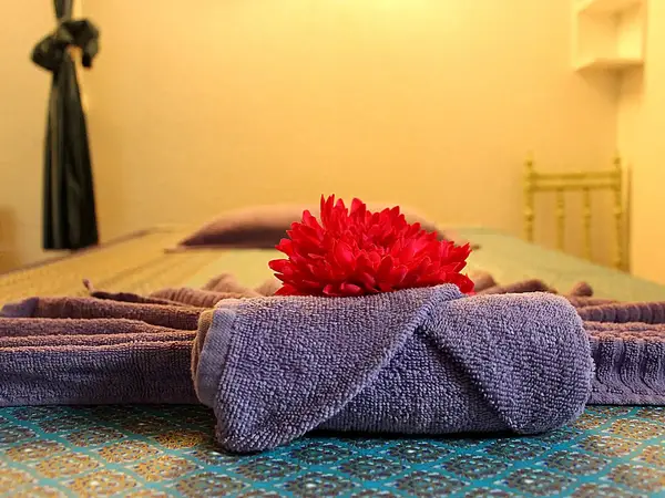 Massage table with folded towels and red flower in a softly lit room