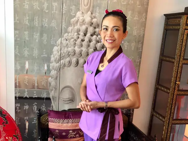 Thai massage room with purple-clad staff, ornate decor, and Buddha backdrop