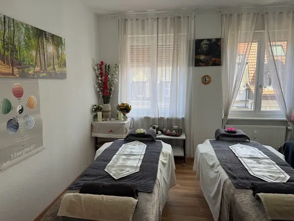 Bright massage room with two treatment tables, curtains, and wall art
